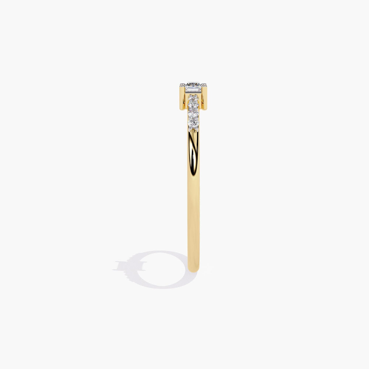 A thin yellow gold band with a small rectangular diamond in the center and smaller round diamonds on either side of the center stone.