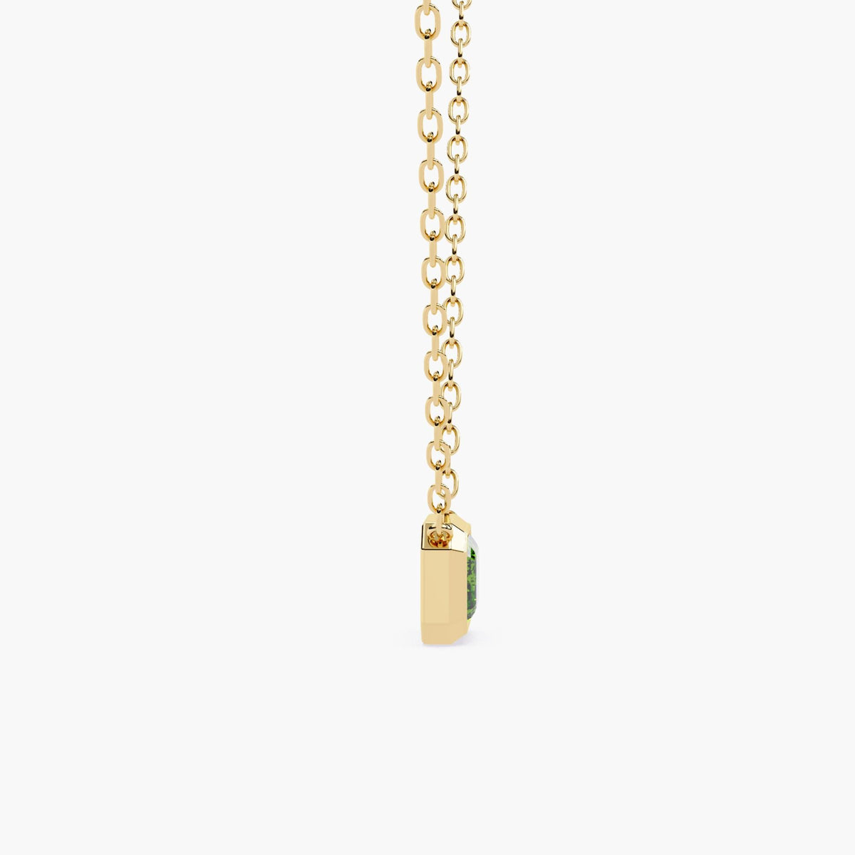 A gold chain necklace with a rectangular green diamond pendant.