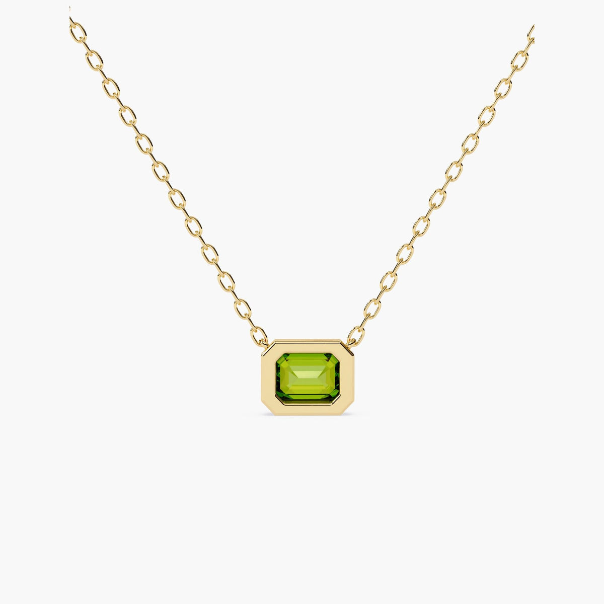 A gold chain necklace with a rectangular green diamond pendant.