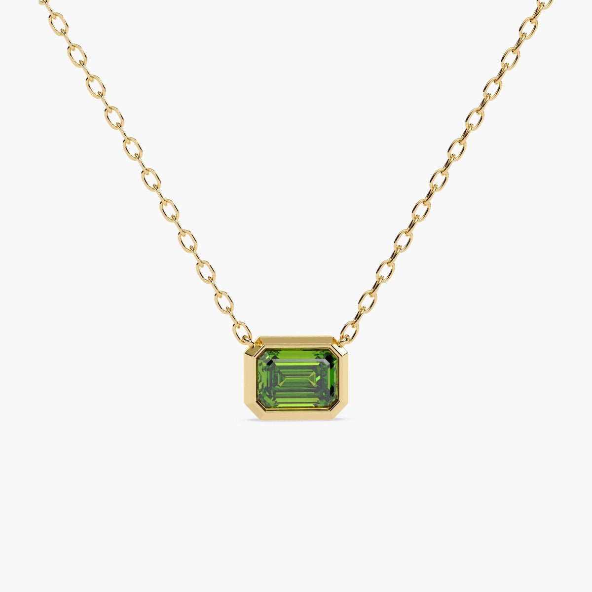 A gold chain necklace with a rectangular green diamond pendant.