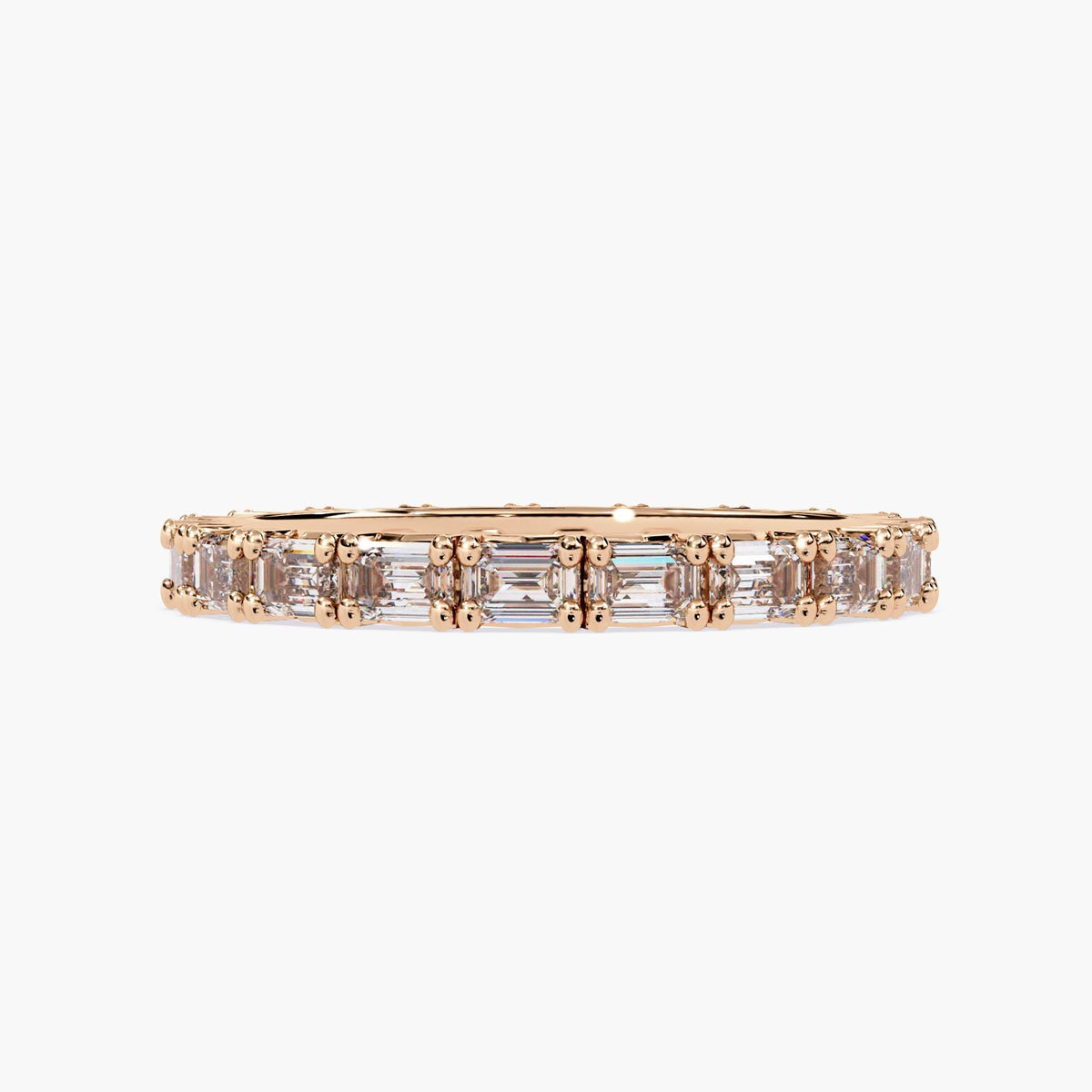 A rose gold band with a row of emerald cut diamonds.