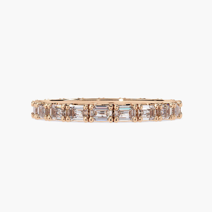 A rose gold band with a row of emerald cut diamonds.