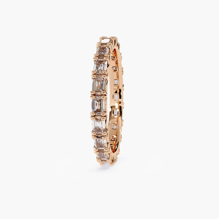 A rose gold band with a row of emerald cut diamonds.