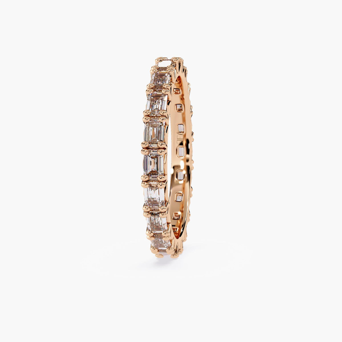 A rose gold band with a row of emerald cut diamonds.