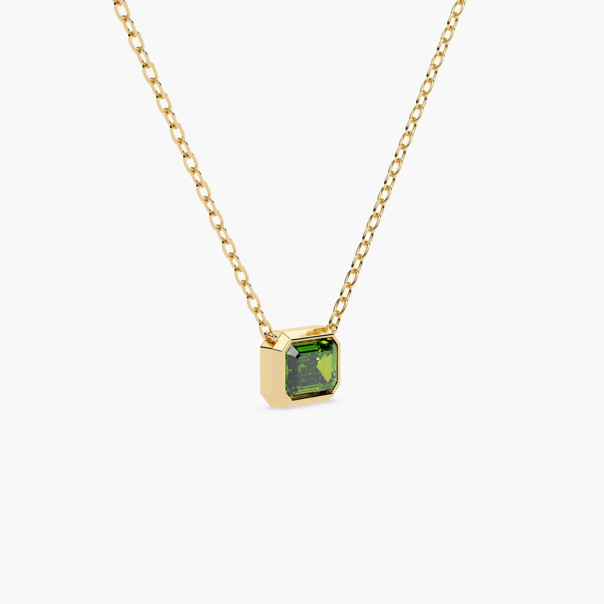 A gold chain necklace with a rectangular green diamond pendant.