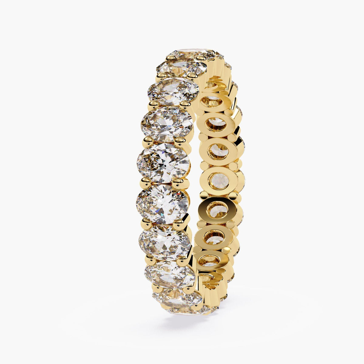 A gold band ring with a row of oval shaped diamonds set in a pave setting.