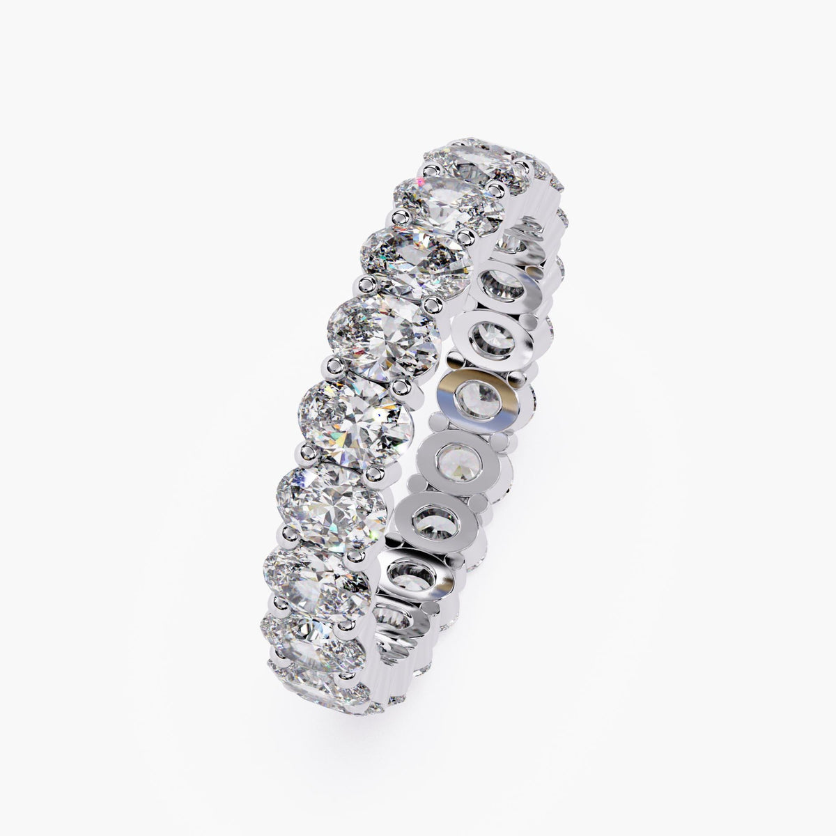 A white gold band ring with a row of oval shaped diamonds set in a pave setting.