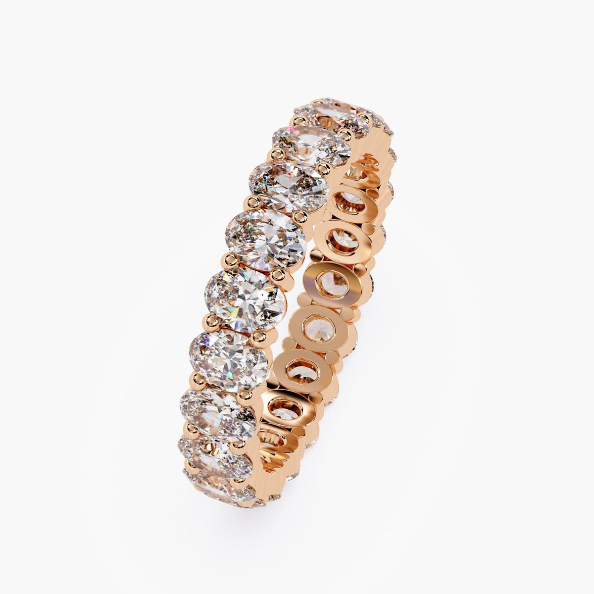 A rose gold band ring with a row of oval shaped diamonds set in a pave setting.
