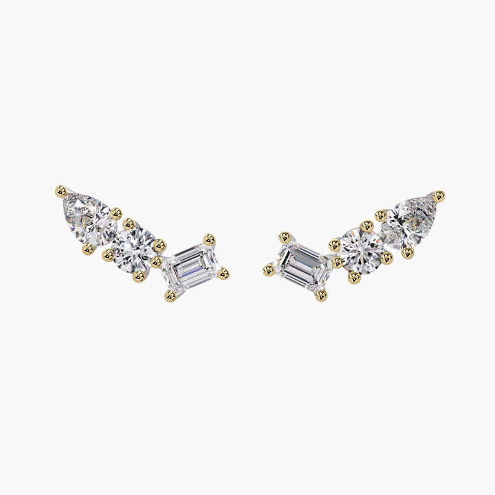 A pair of 14k yellow gold ear climber earrings featuring lab-grown diamonds in pear, round, and emerald cuts arranged in a curved cluster design.