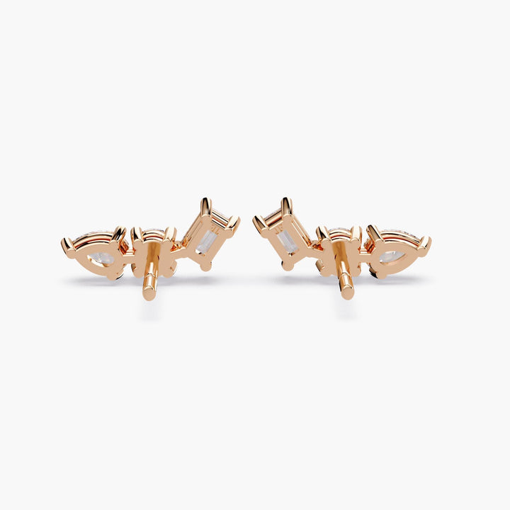 A pair of gold earrings featuring a curved cluster of clear lab-grown diamonds. The earrings are set with pear, round, and emerald cut stones, arranged to follow the curve of the ear.