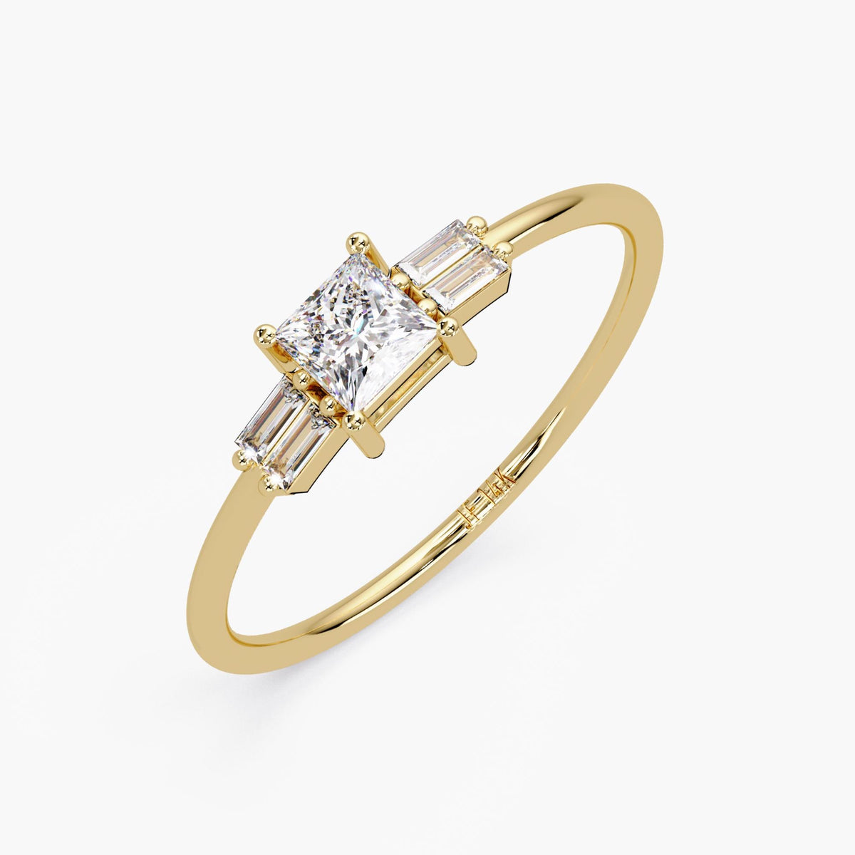 Angled viee of the 14K yellow gold ring with princess cut center diamond and baguette diamond accents. It show cases the thin band ring