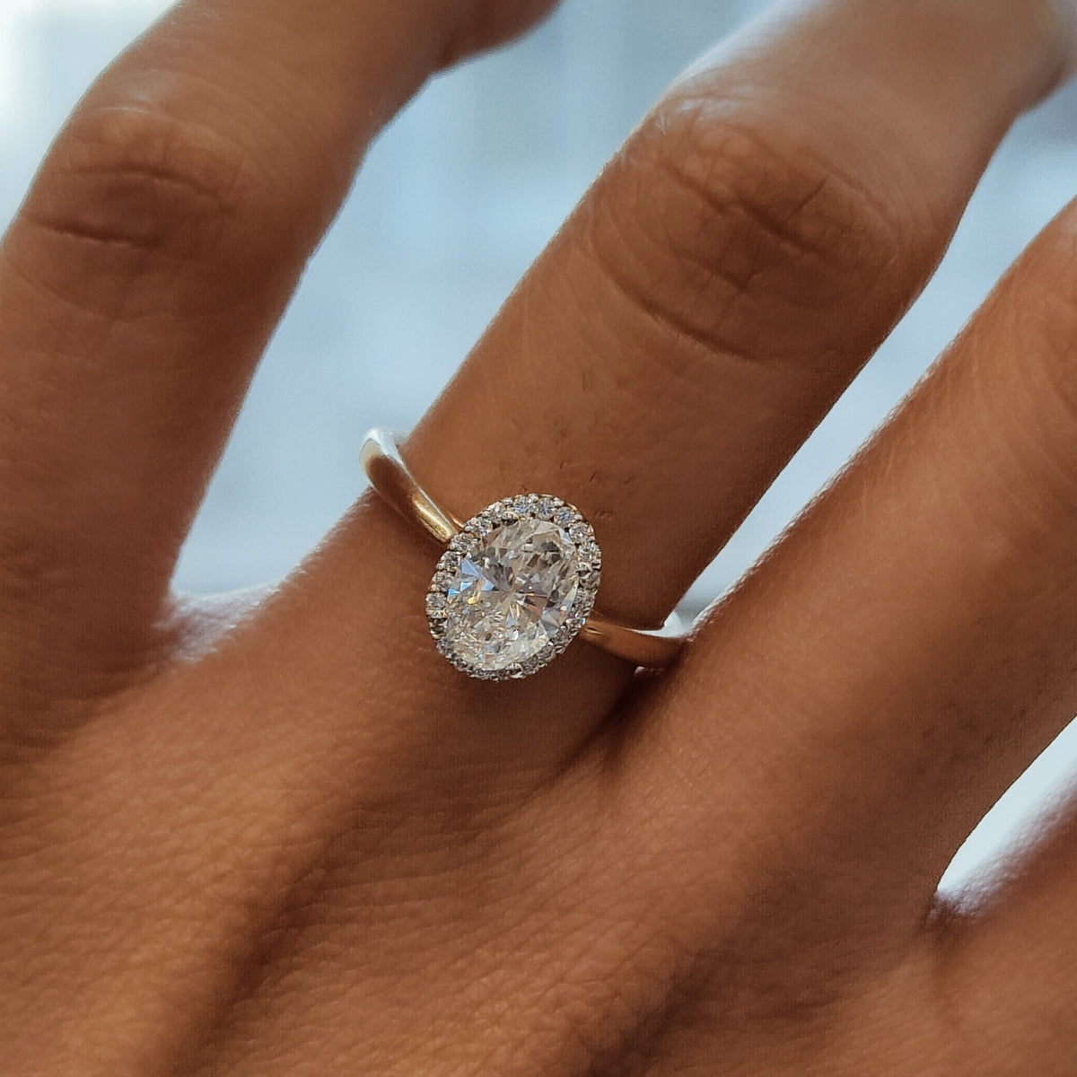 May include: A gold ring with an oval-shaped diamond center stone surrounded by a halo of smaller diamonds.