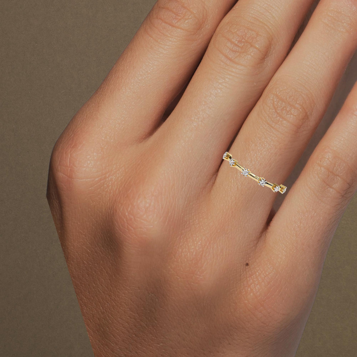 14k yellow gold floating diamond ring worn on a woman's hand. The six round natural diamonds are spaced evenly along the slim band, sitting delicately across the finger for a light, minimalist look. Ideal for stacking or wearing solo.