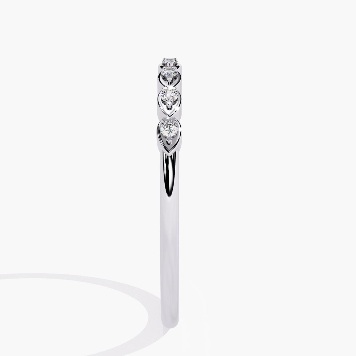 14k white gold band featuring seven round diamonds set in alternating pear-shaped bezels, showing the slim profile and low-setting design of the stacking ring.