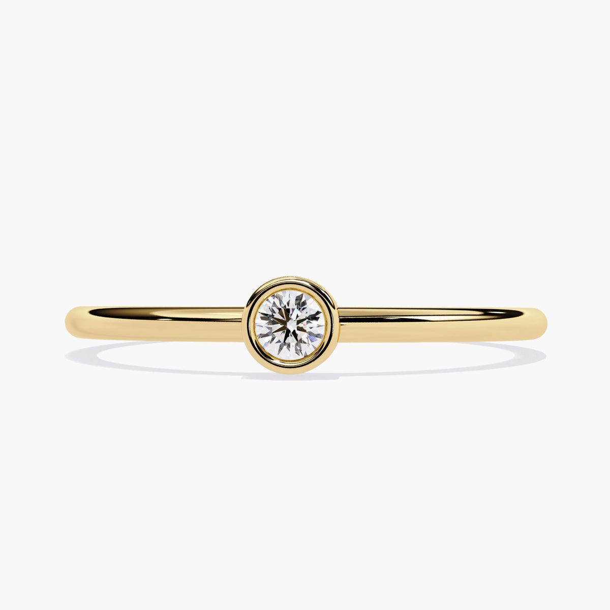 14k yellow gold bezel set solitaire ring featuring a single round natural diamond in the center. The diamond is secured in a smooth bezel setting on a thin, polished gold band.