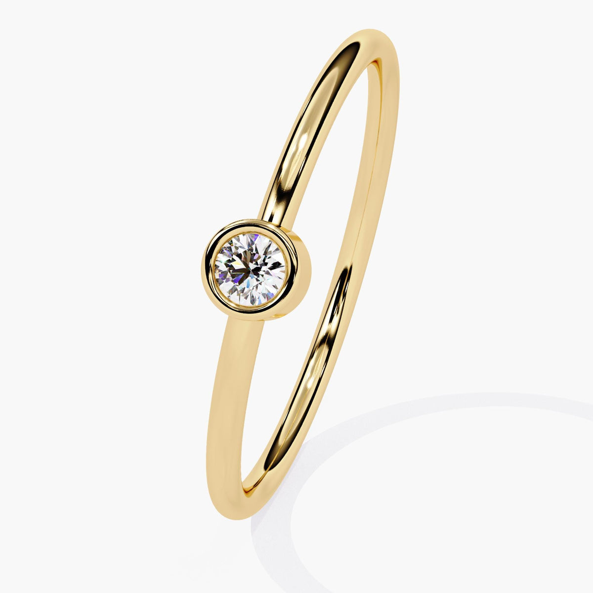 14k yellow gold solitaire ring featuring a round natural diamond in a bezel setting. The slim polished band curves gently around the finger, highlighting the centered diamond’s sparkle.