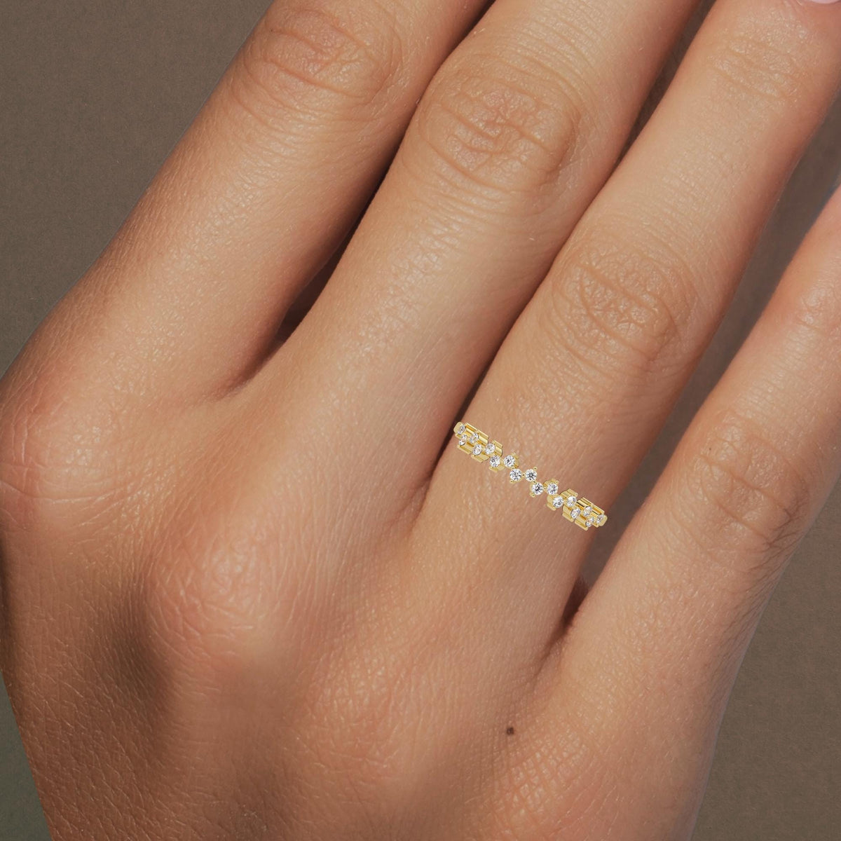 Close-up of a hand wearing a 14K yellow gold zig zag diamond ring. The ring features a delicate wave of small round diamonds, evenly spaced across the finger. The polished gold band enhances the sparkle of each diamond.