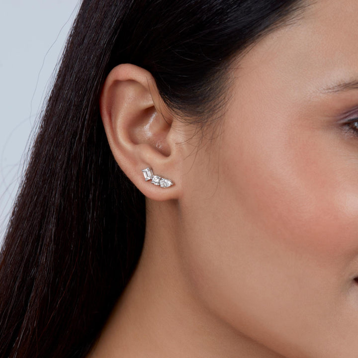 Model wearing a curved diamond ear climber in white gold with pear, round, and emerald cut lab-grown diamonds, styled as a minimalist everyday stud.
