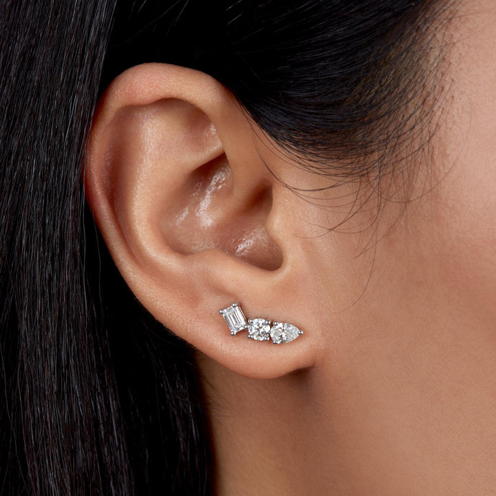 Close-up of a woman wearing a curved ear climber earring with lab-grown diamonds in emerald, round, and pear cuts set in white gold, following the natural curve of the ear.