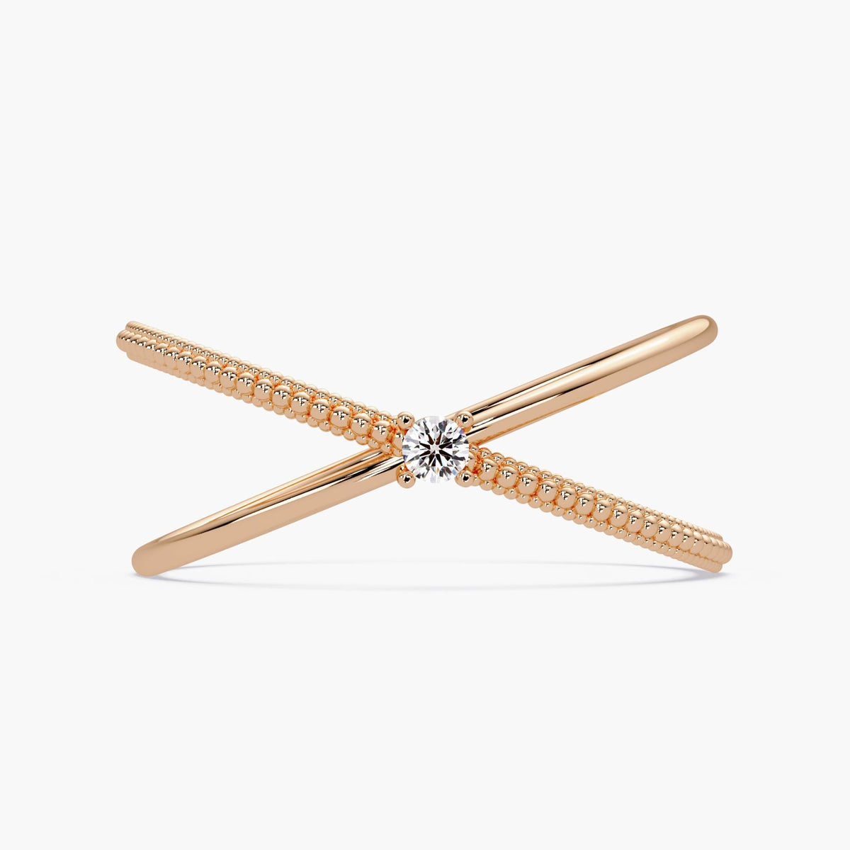 14k rose gold criss cross ring featuring a round natural diamond at the center, with one polished band crossing over a beaded gold band in an X-ring design.