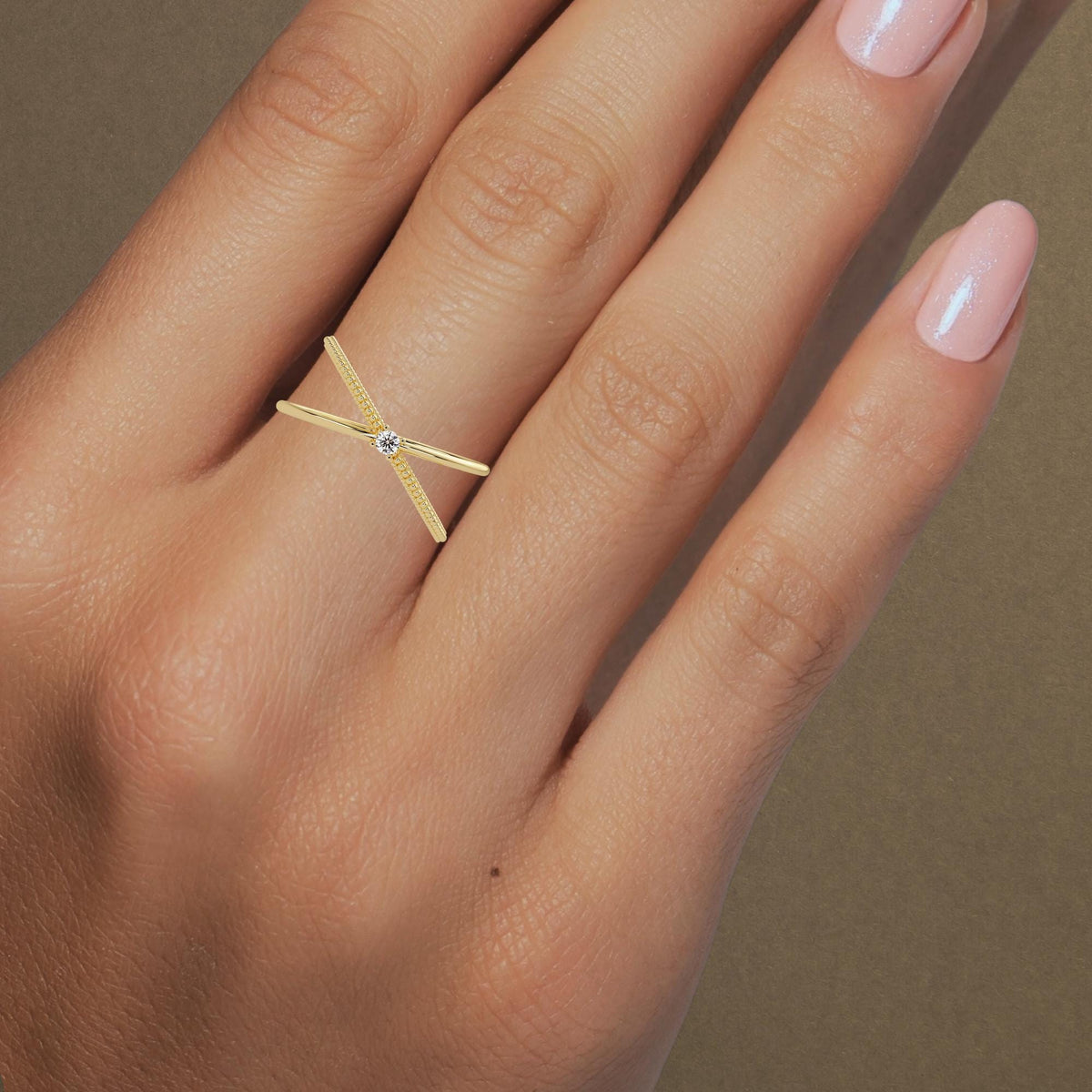 14k gold criss cross ring featuring a round natural diamond at the center, with one polished band crossing over a beaded gold band in an X-ring design.
