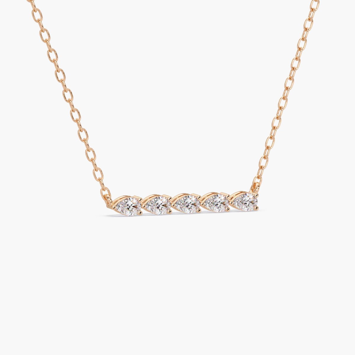 horizontal pear diamond bar necklace in 14k rose gold, showcasing five prong set lab-grown pear diamonds aligned in a row. The diamonds create a gentle curve, catching light from different angles, with a fine chain attached on both sides.