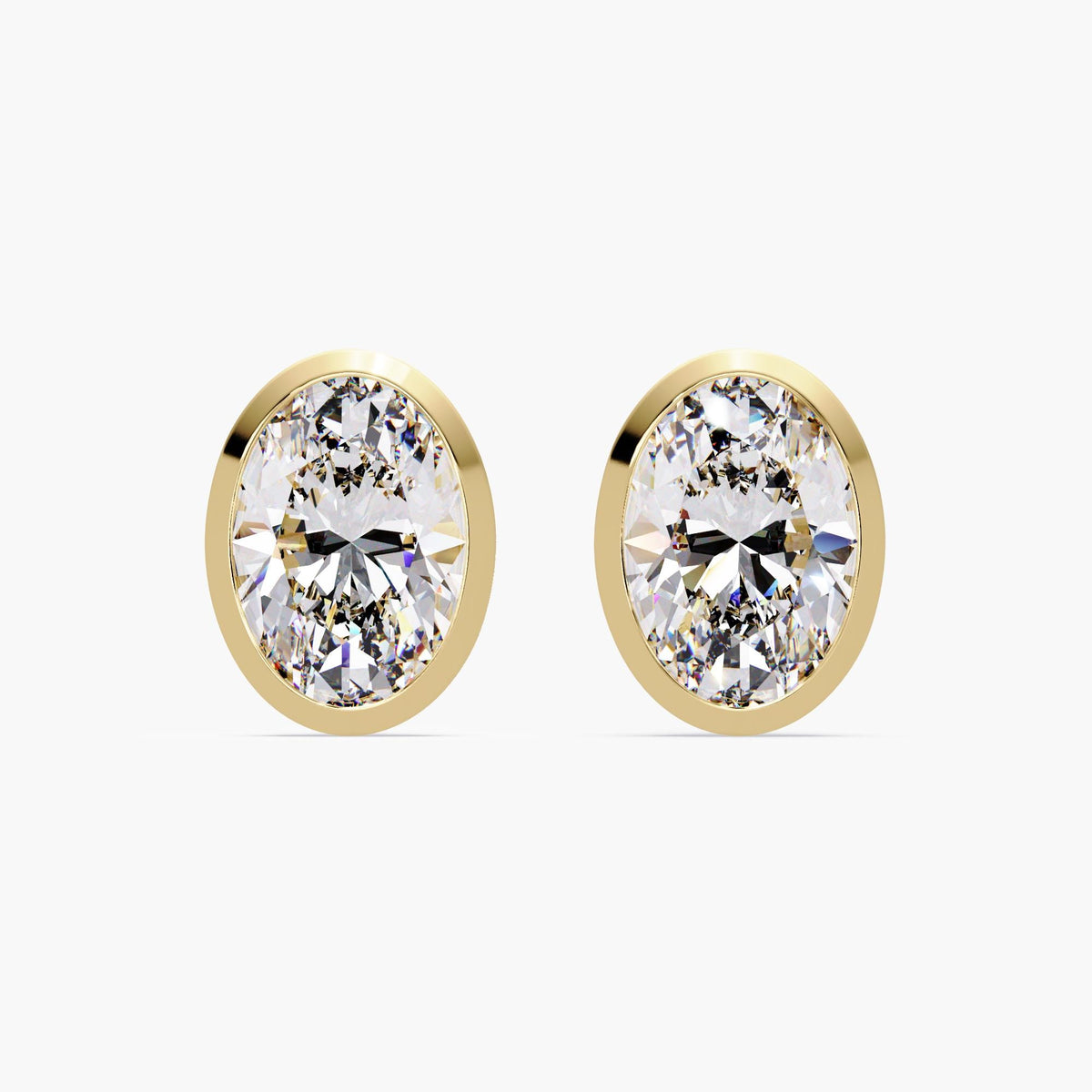 14k yellow gold oval diamond stud earrings featuring bezel set lab grown diamonds. The low-profile setting sits flush against the ear for a clean and modern look.