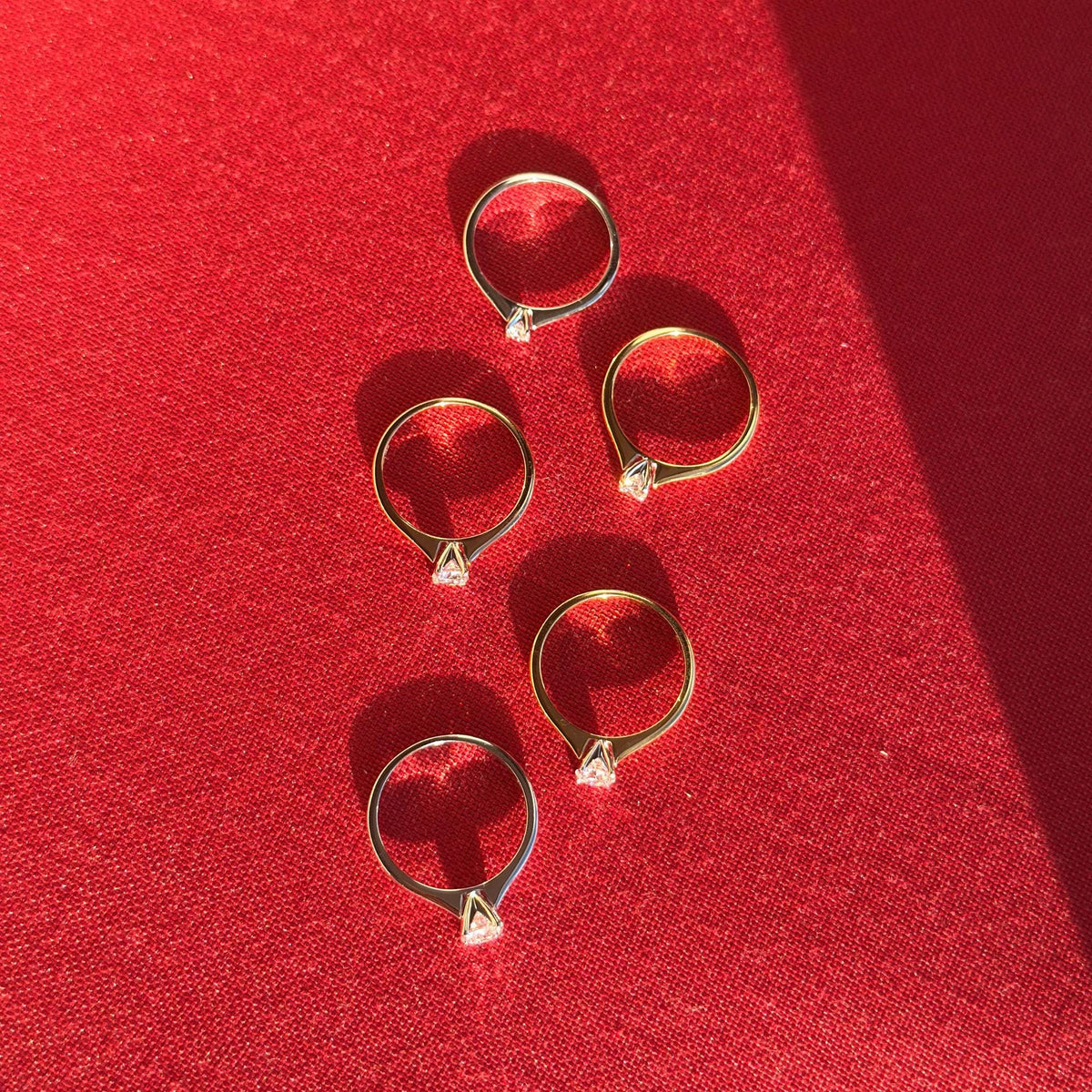 Overhead view of five 18K yellow gold solitaire rings with round lab-grown diamonds in white gold prong settings.