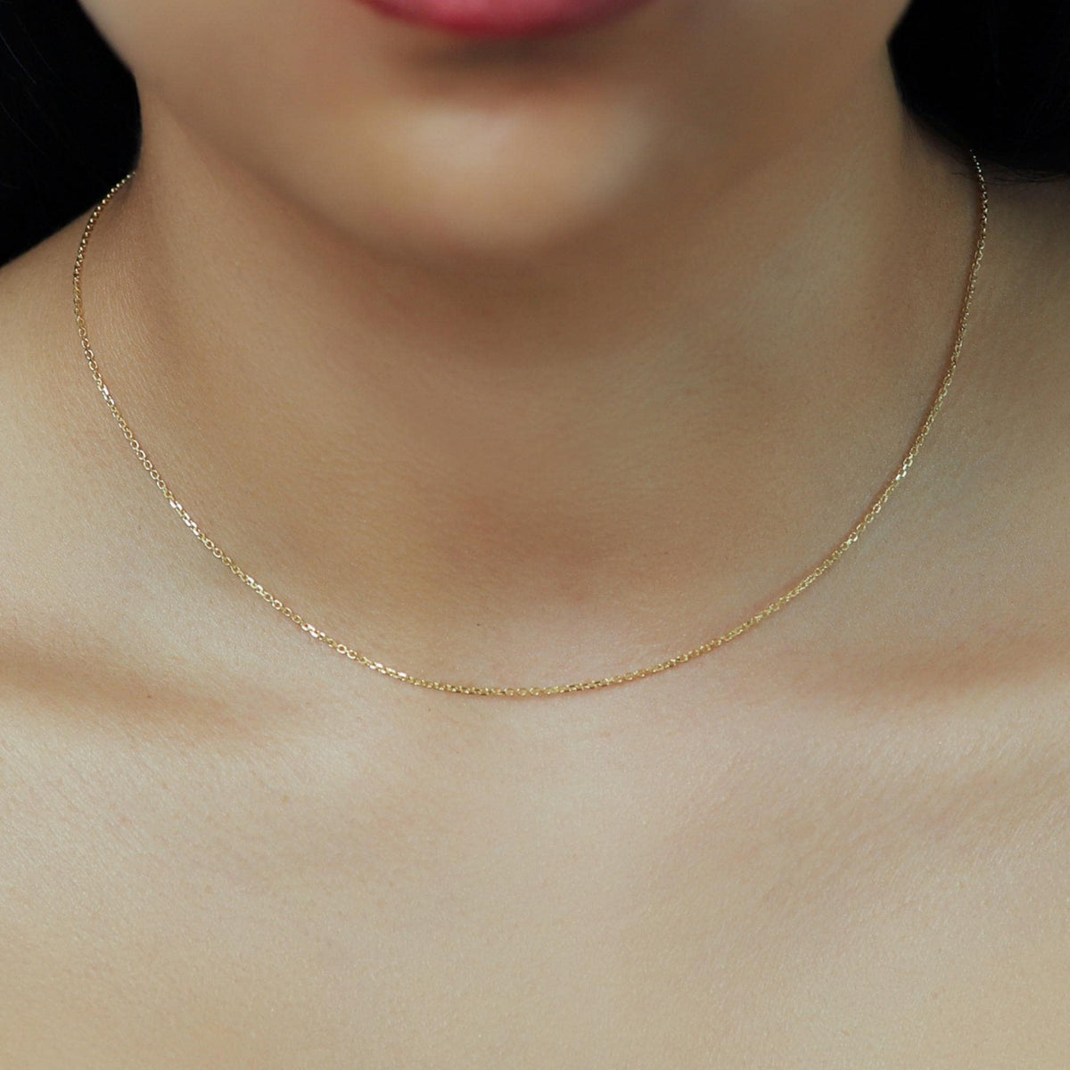 14k solid gold dainty cable chain necklace worn close to the neck, showcasing 0.9mm diamond-cut links with a subtle shine, ideal for everyday layering or minimalist style
