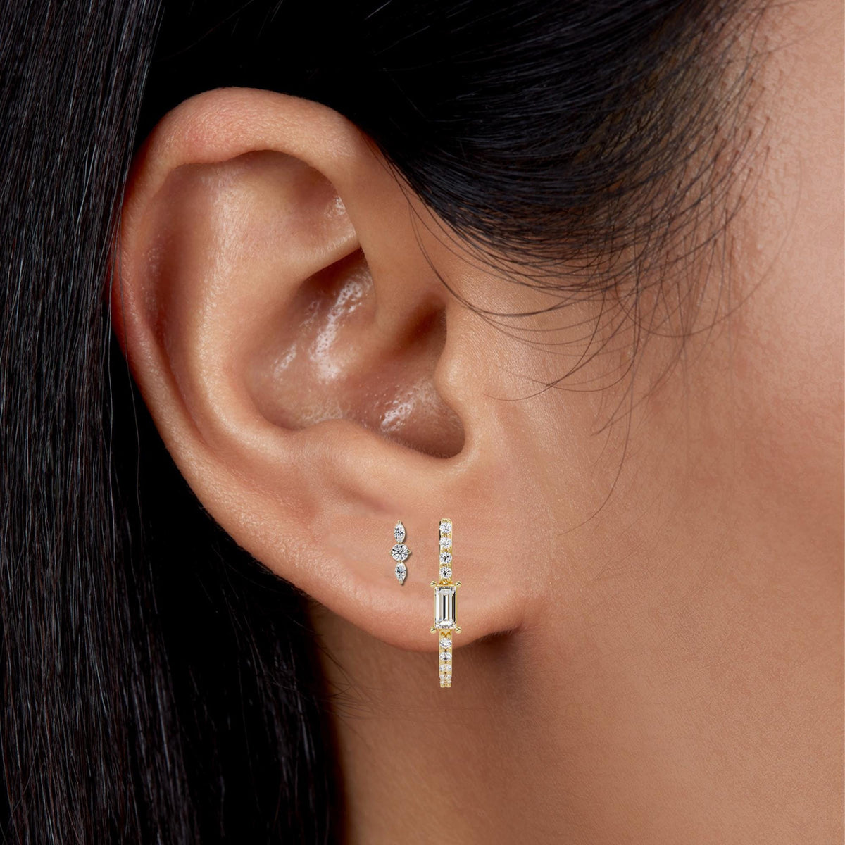 Model wearing a stack of three 14K gold lab-grown diamond earrings, featuring a marquise and round curved stud in the second piercing