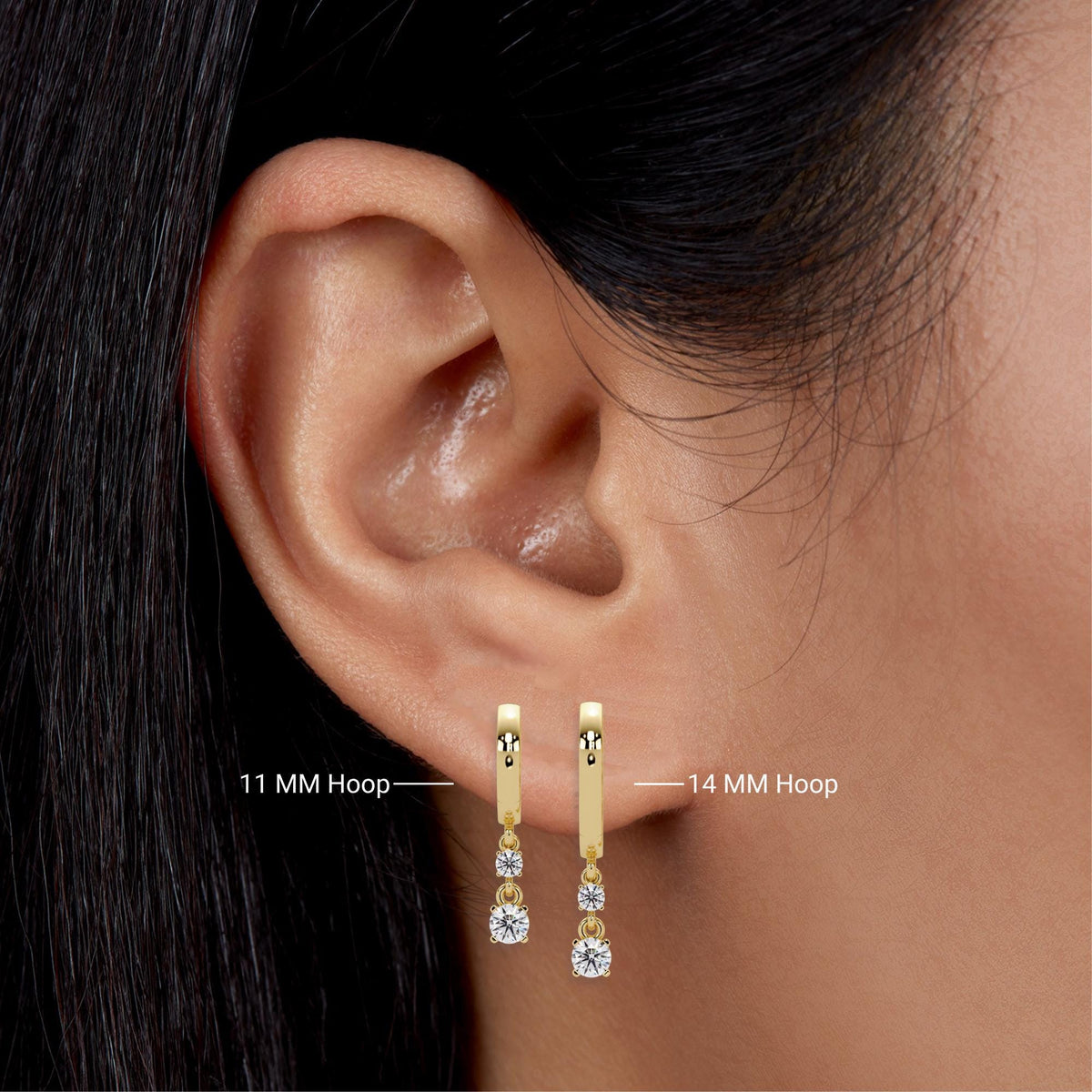 14K gold double diamond drop huggie earrings in two sizes, 11mm and 14mm hoops, shown side by side on ear for size comparison