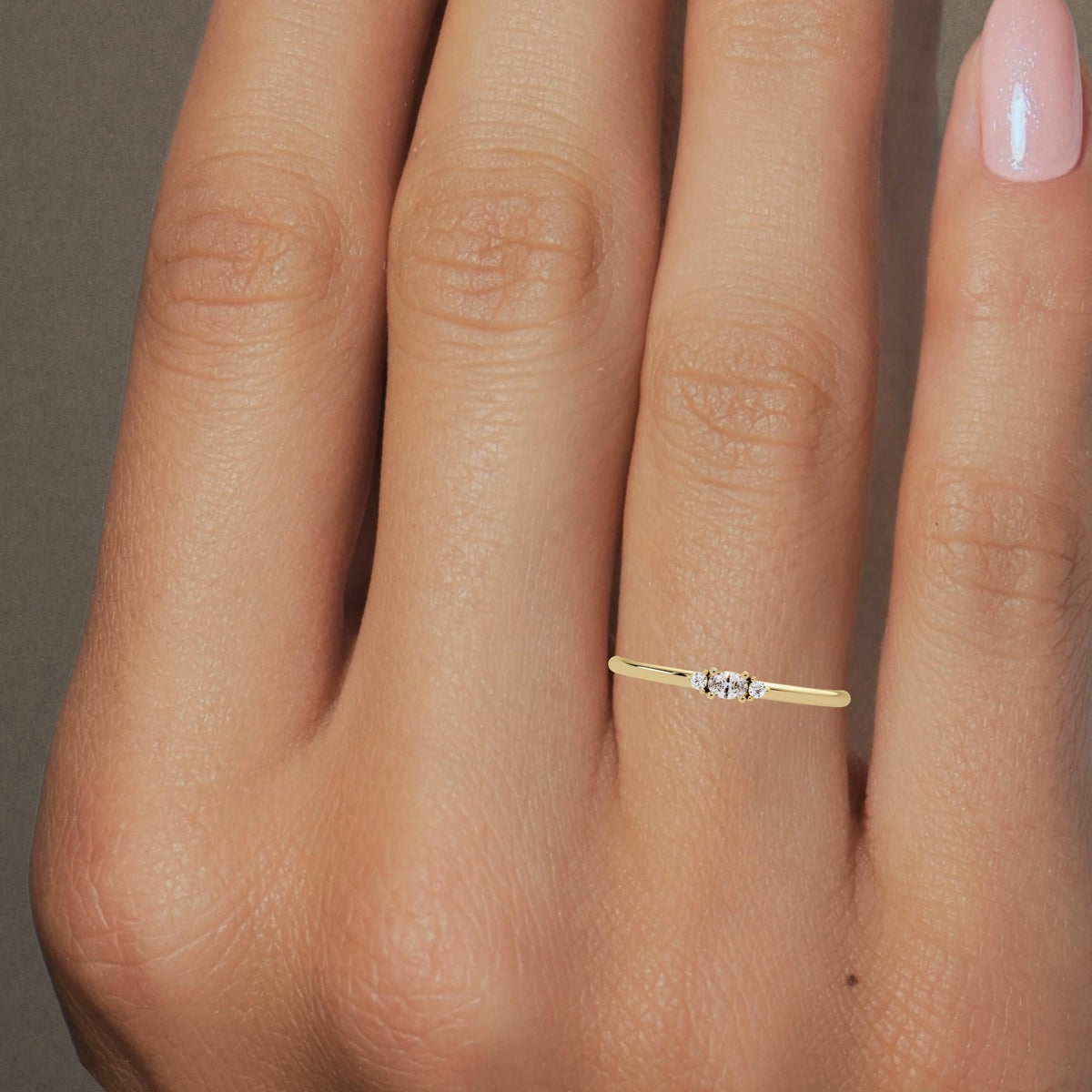 14K yellow gold ring with three lab-grown diamonds — a center oval flanked by two round stones — on a thin 1.3mm band.