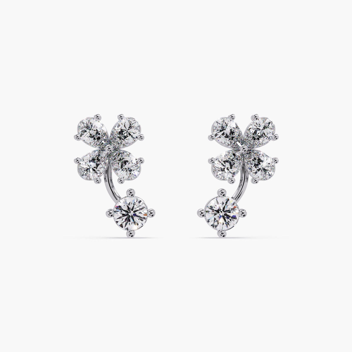 White gold diamond clover earrings with floral cluster design, featuring four pear-cut lab-grown diamonds and a round diamond drop. Sculptural solid 14K gold studs with prong-set stones