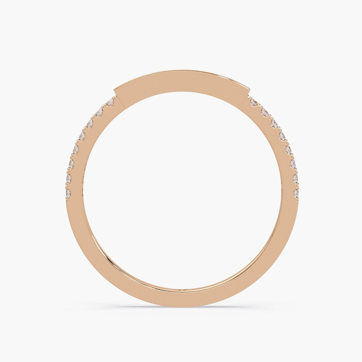 14K rose gold diamond ring showing the thin band structure. The round pavé-set diamonds are visible along the outer half of the band, leading to a solid rectangular channel bar at the top where emerald-cut diamonds are set horizontally. The photo emphasizes the ring’s slim band thickness and bar height from a direct side view.