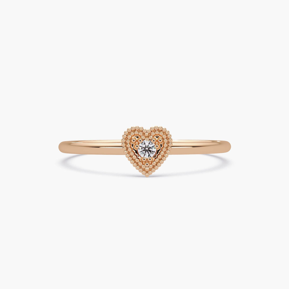 This is a dainty 14K rose gold ring featuring a small beaded heart with a sparkling diamond in the center.