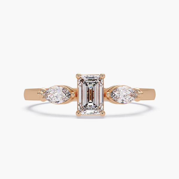 14k rose gold emerald cut and pear diamond ring on white background