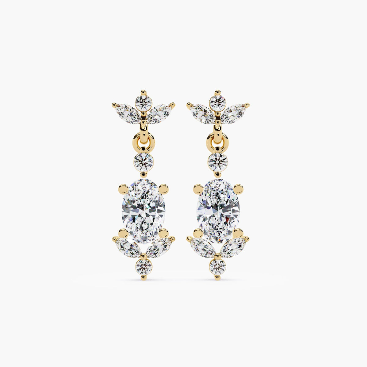 May include: A pair of gold dangle earrings with oval-shaped diamonds. Each earring has a cluster of smaller diamonds surrounding the larger diamond. The earrings have a delicate, feminine design.