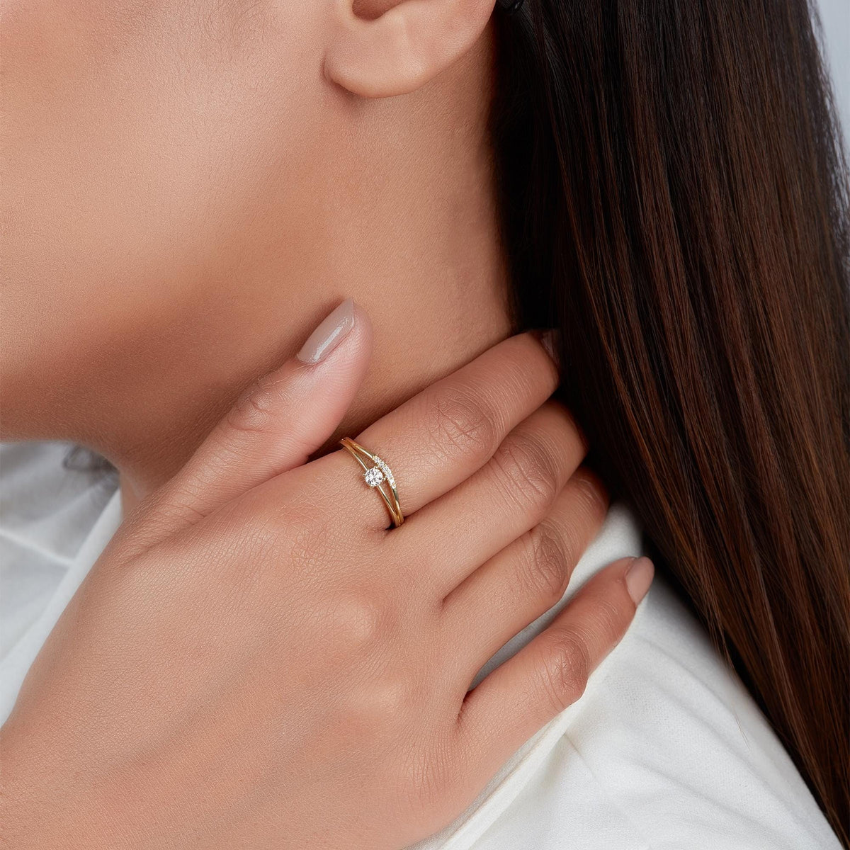 14K yellow gold diamond bridal set on her ring finger, featuring a small solitaire engagement ring and a curved diamond enhancer band.