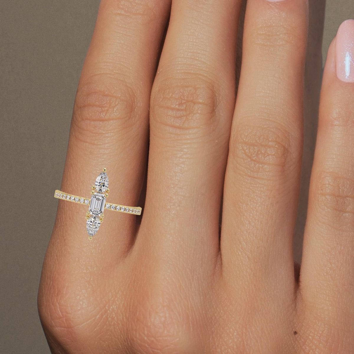 Three-stone vertical lab diamond ring with emerald and pear cuts on hand