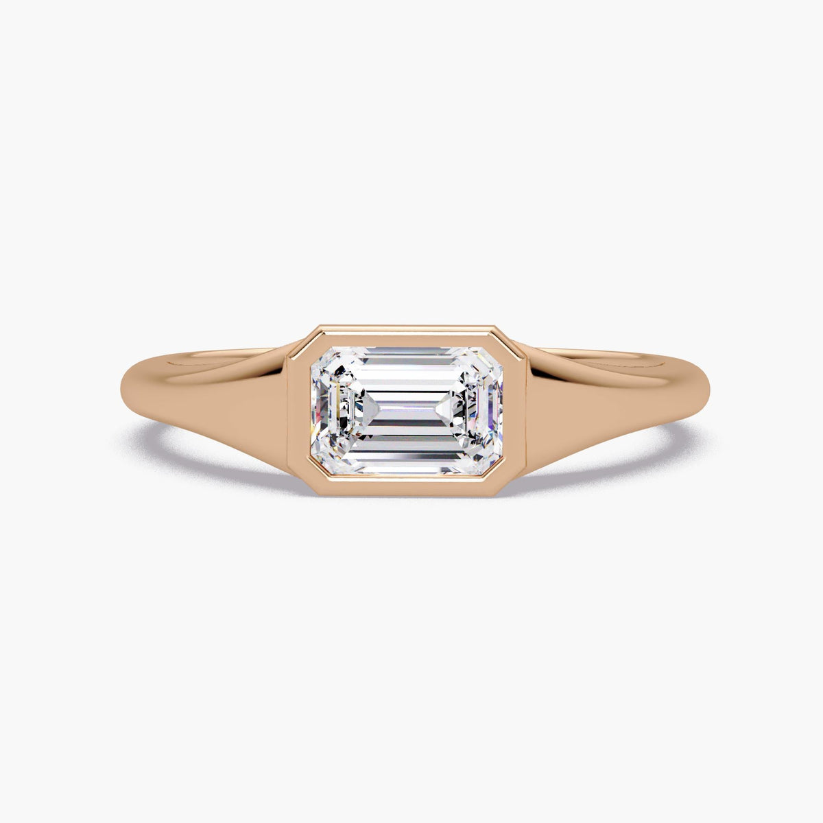 Emerald cut lab diamond signet ring in 14K rose gold with a bezel-set center stone and smooth tapered band, styled as a modern pinky or statement ring for everyday wear.