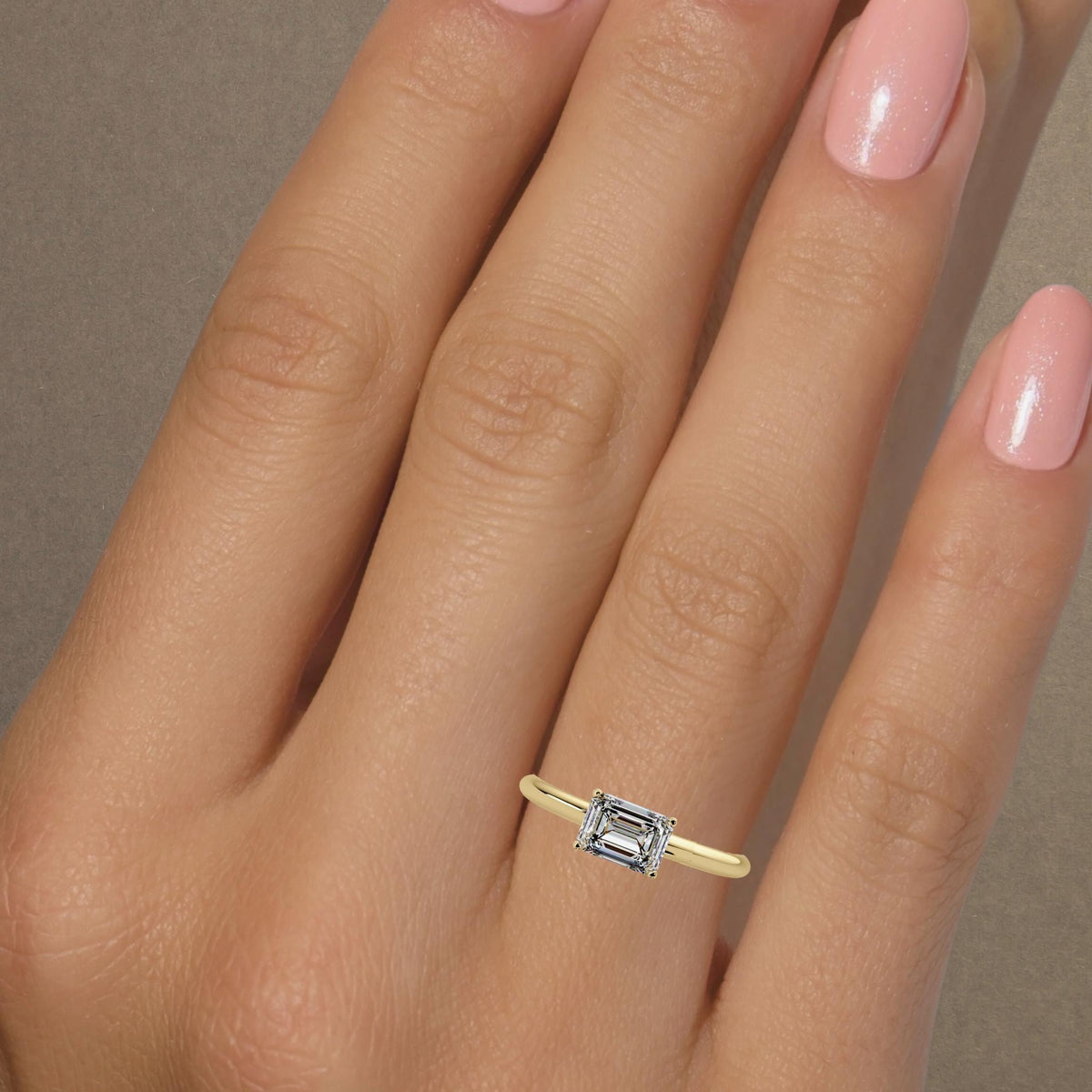1CT emerald cut lab diamond east west ring on hand, thin 14K gold solitaire engagement ring that stacks easily and looks like a modern statement ring