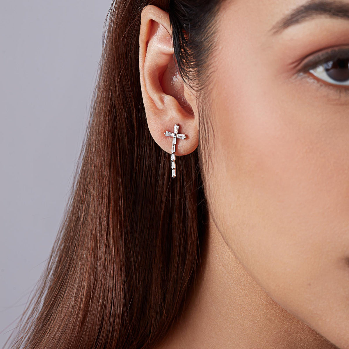 Diamond cross stud earrings in 14k gold worn on ear