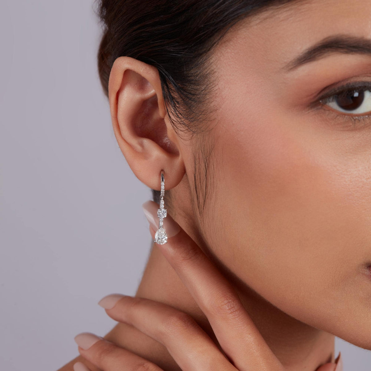 On ear view of pear diamond drop earrings in 14k gold