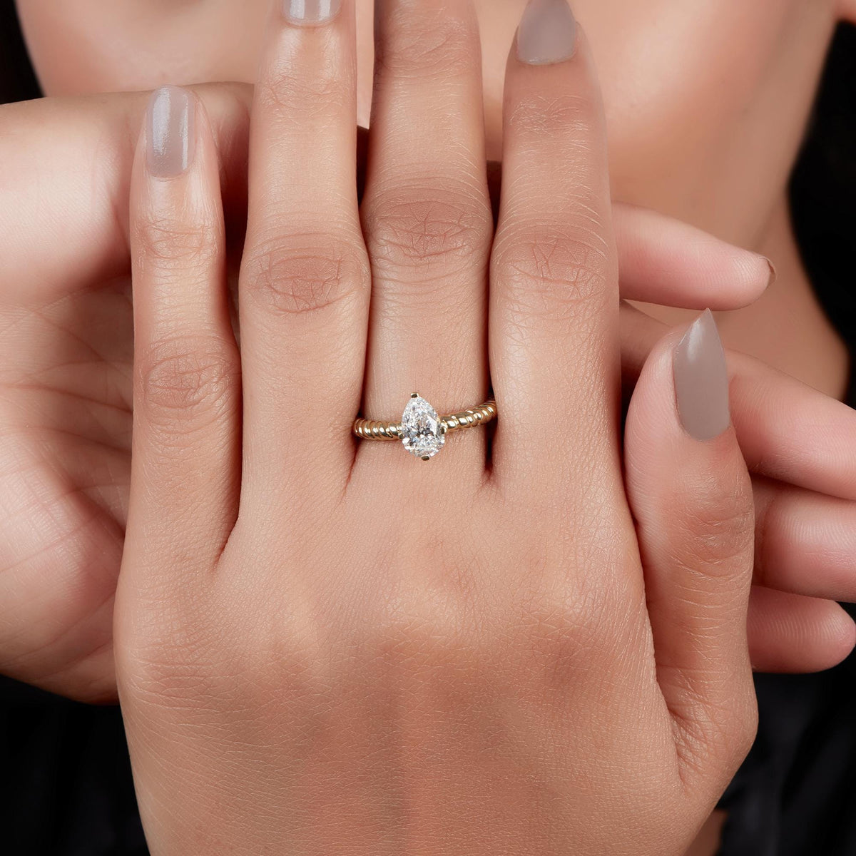 14K yellow gold ring featuring a pear-shaped diamond solitaire on a beaded band.