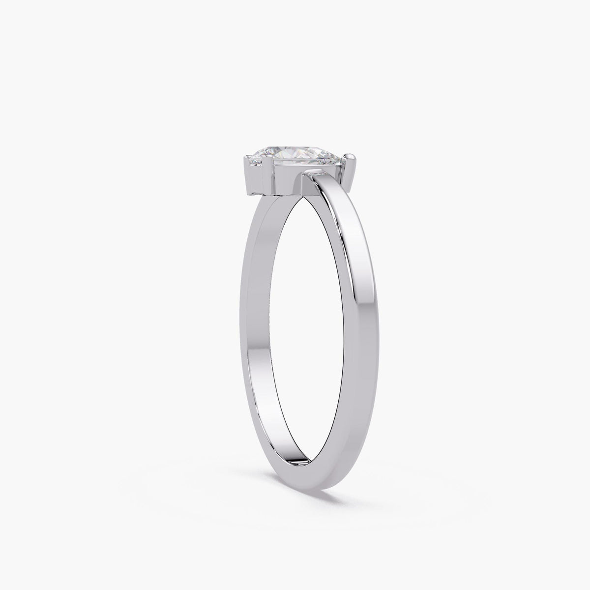 The 14K white gold ring shown from the side, highlighting the pear diamond’s three-prong basket and slim band profile.