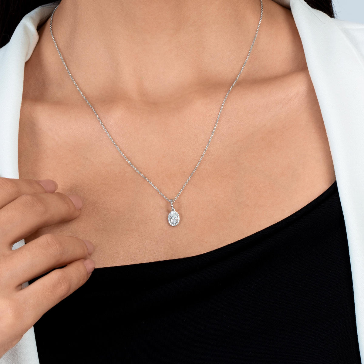 14K gold oval halo natural diamond pendant necklace with 0.50 CTW diamonds on a dainty chain, worn at the neckline.