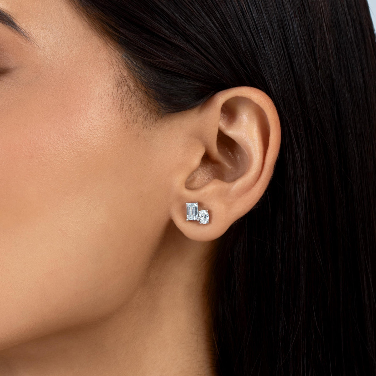 14K gold lab-grown diamond stud earring featuring emerald and oval-cut colorless diamonds in prong settings, worn on an ear.