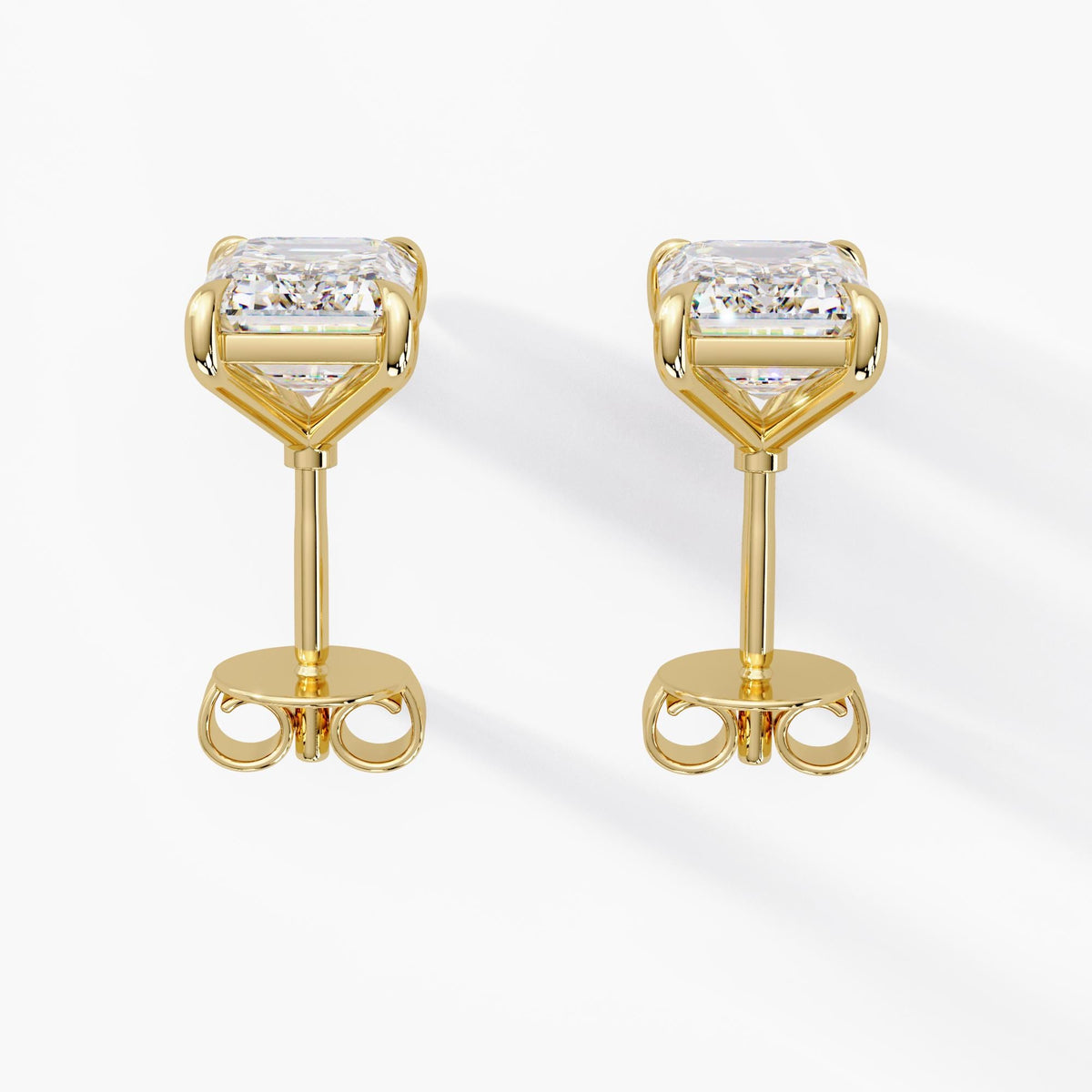 Pair of 14k yellow gold emerald cut lab grown diamond stud earrings with open four claw settings, straight posts and pushback closures for weddings and bridal jewelry gifts