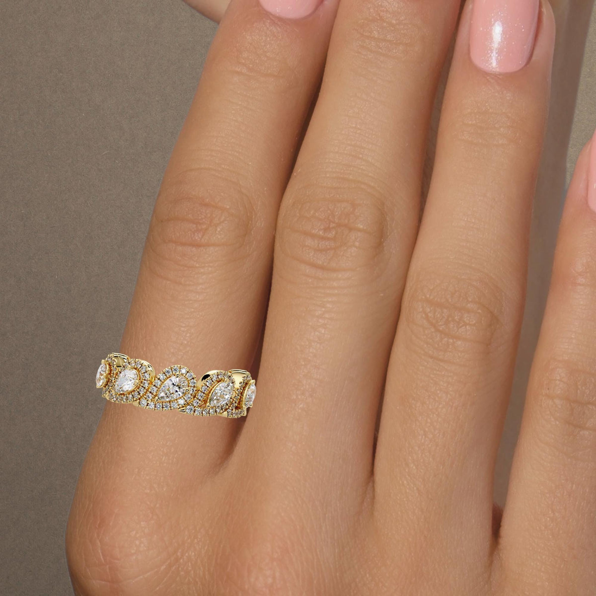 Pear diamond wedding band worn on a hand / Yellow gold teardrop halos with round pavé diamonds / Wide scalloped anniversary ring