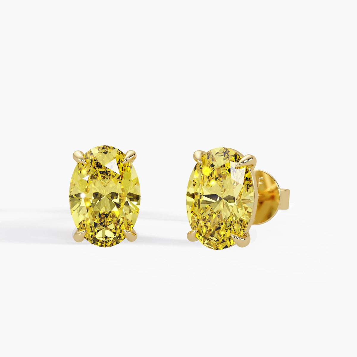 Oval fancy intense yellow lab grown diamond stud earrings in 14K yellow gold with four claw prongs and pushback closures